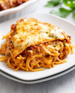 A slice of Spaghetti Pie on a stack of white plates.