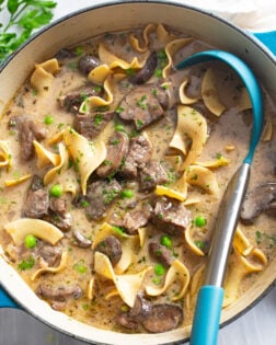 Beef Stroganoff Soup in a soup pot with beef, mushrooms, and egg noodles with parsley on top.