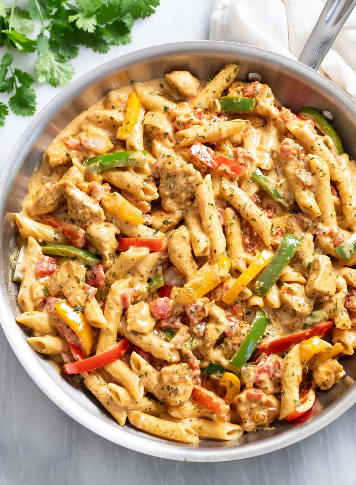 Overhead view of Chicken Fajita Pasta in a skillet with penne pasta in a creamy sauce with chicken and bell peppers.