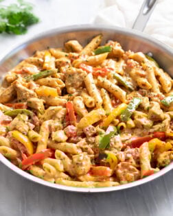 A skillet of Chicken Fajita Pasta with penne, bell peppers, chicken, and a cream sauce.