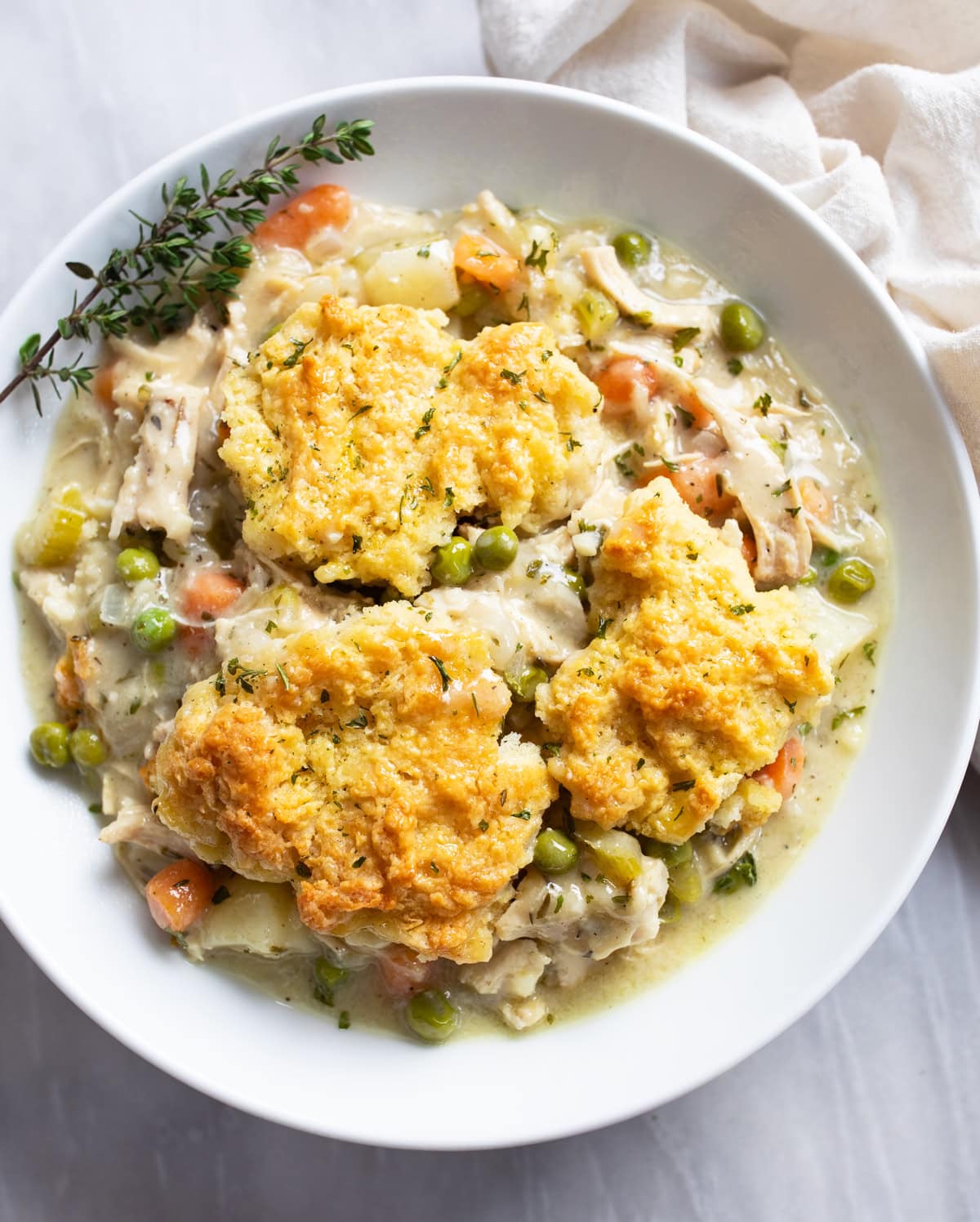 Chicken Pot Pie Casserole in a white bowl with fresh thyme on the side.
