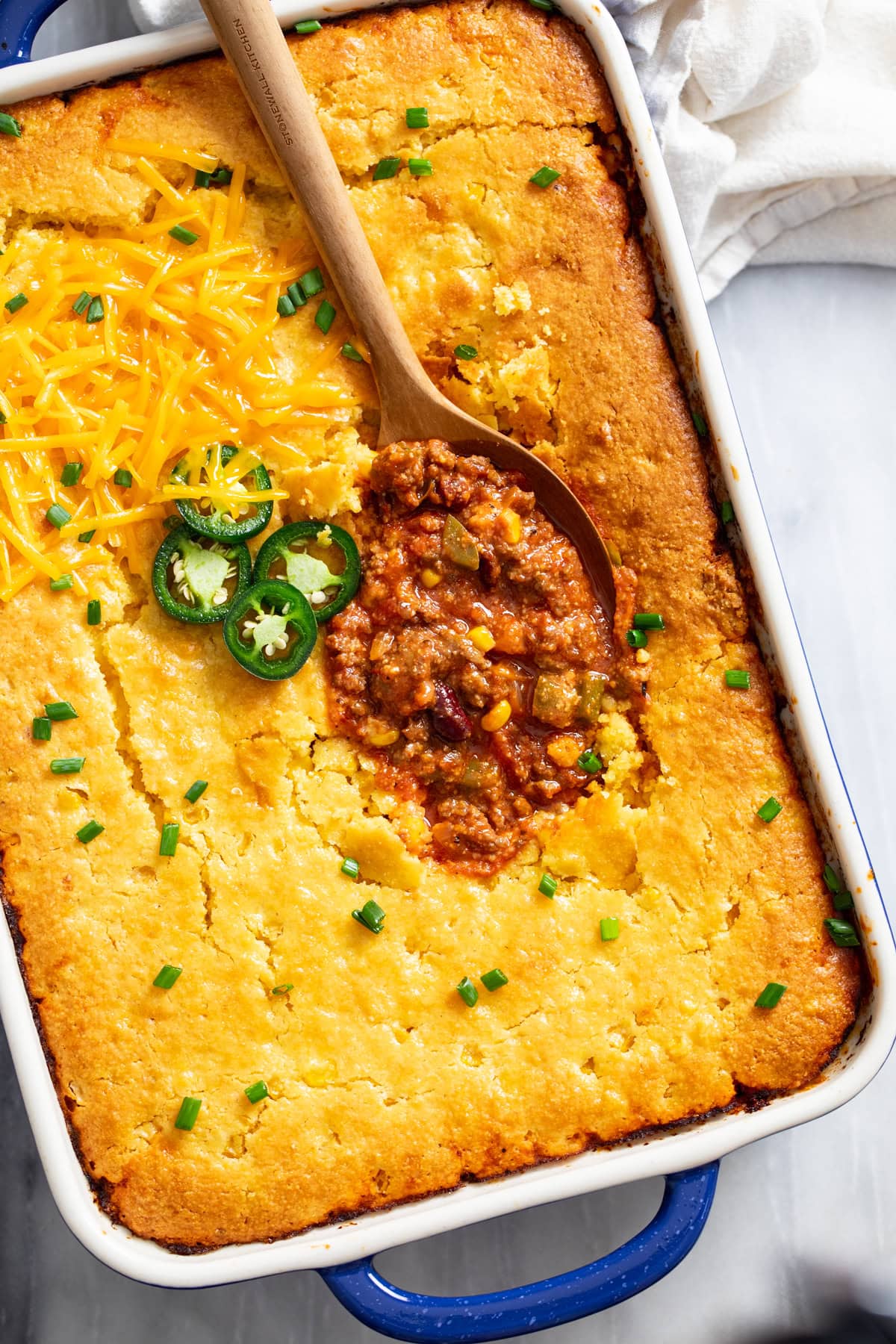 Overhead view of Chili Cornbread Casserole in a baking dish with a spoon scooping it up.