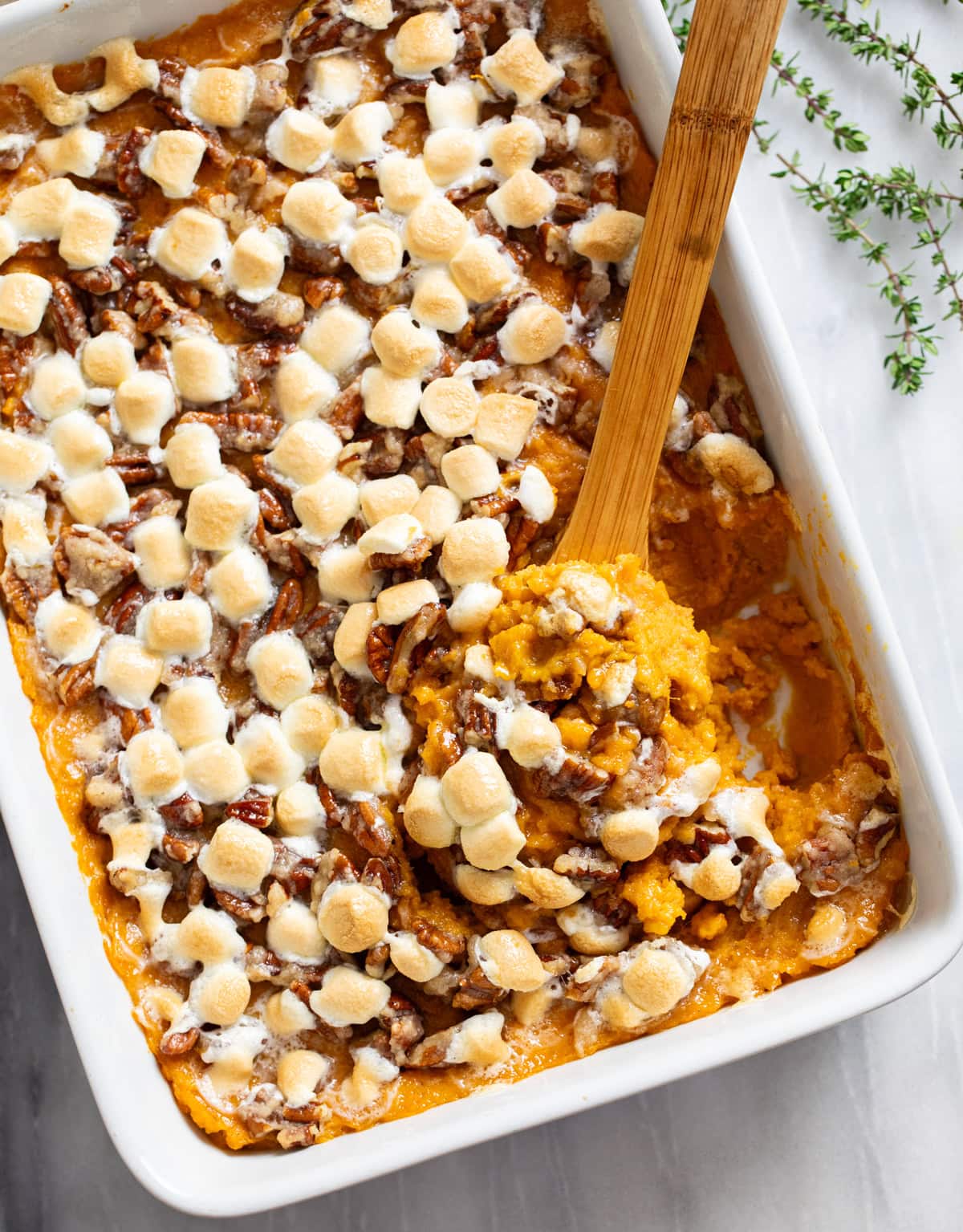 Overhead view of Sweet Potato Casserole in a baking dish with a wooden spoon on the side.