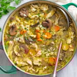 Chicken and Mushroom soup with rice and vegetables in a soup pot with a ladle on the side.