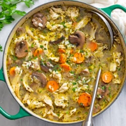 Chicken and Mushroom soup with rice and vegetables in a soup pot with a ladle on the side.