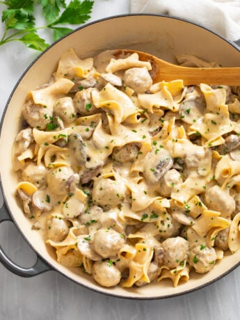 A skillet filled with Meatball Stroganoff in a creamy sauce with egg noodles and mushrooms.