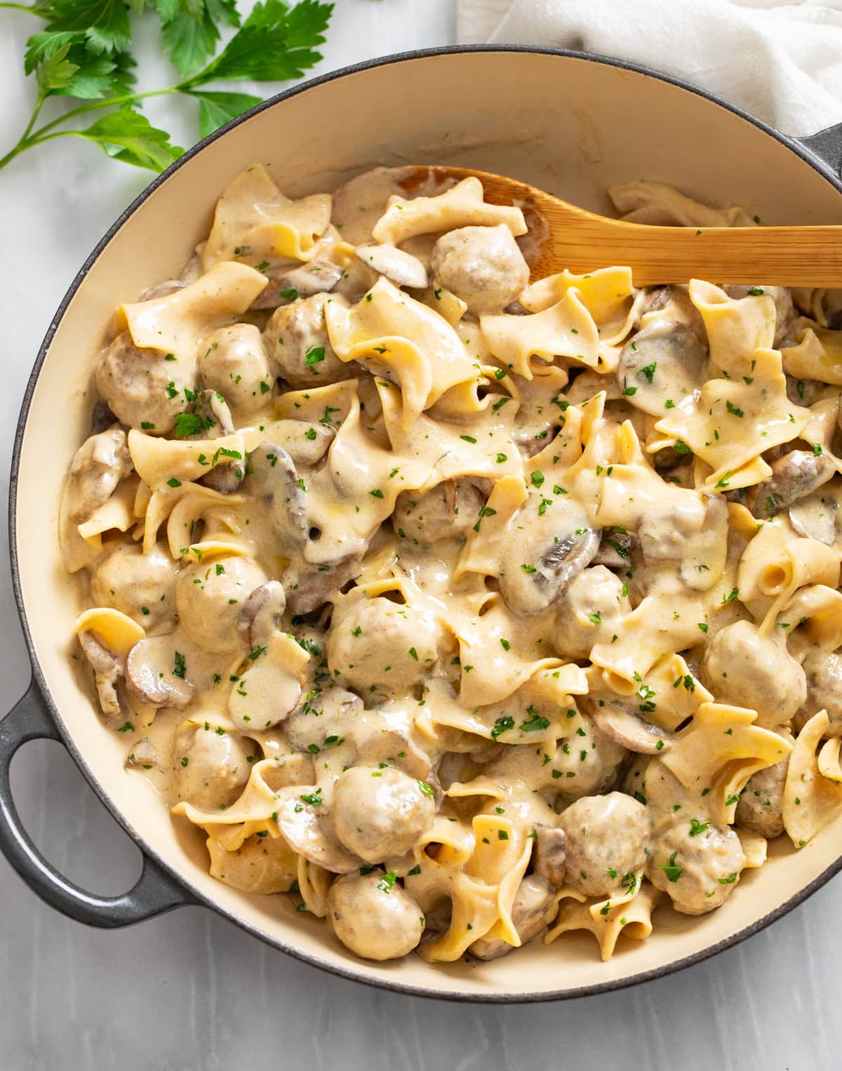 A skillet filled with Meatball Stroganoff in a creamy sauce with egg noodles and mushrooms.
