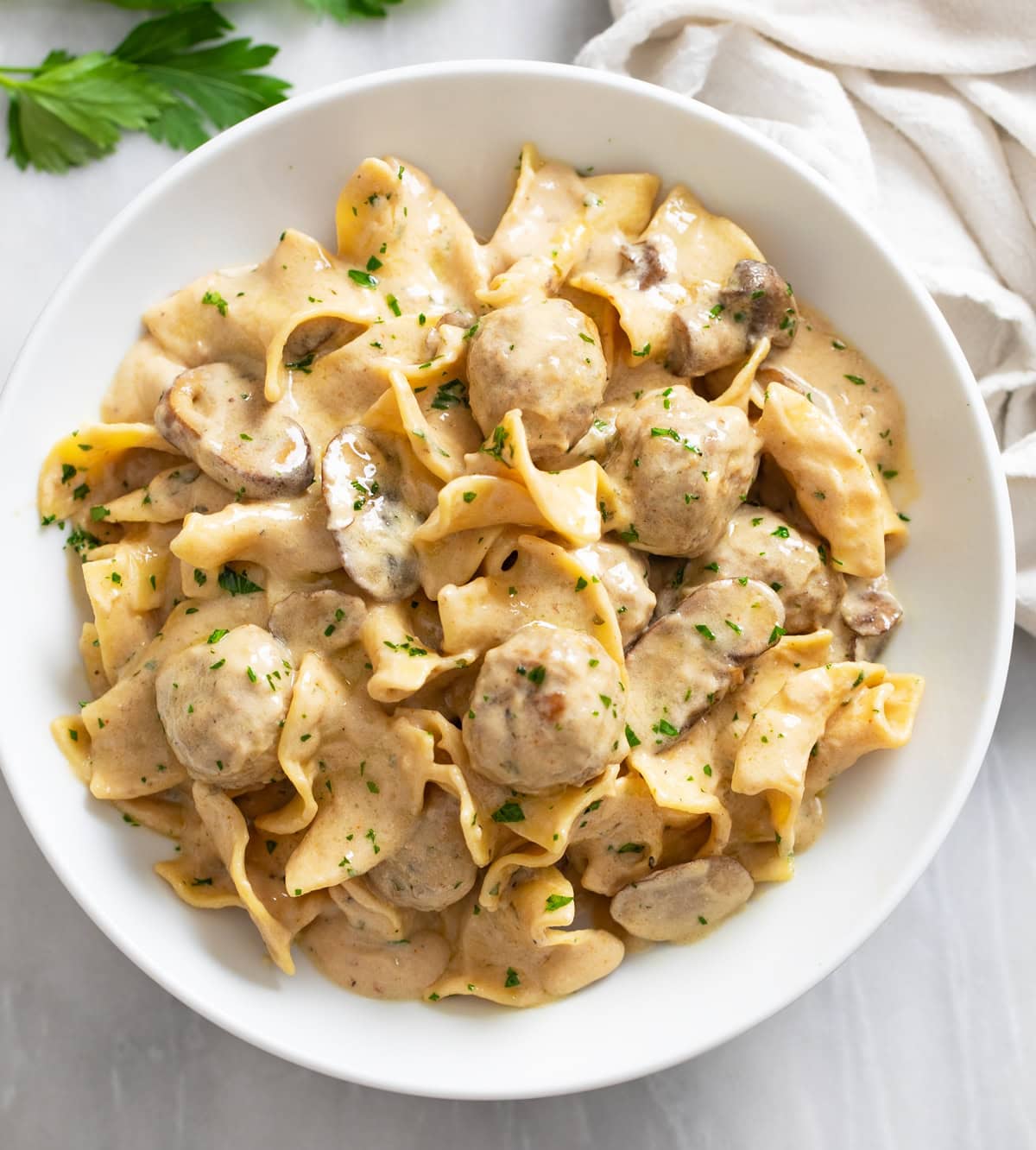 Meatball Stroganoff in a creamy sauce with mushrooms and egg noodles in a white bowl.