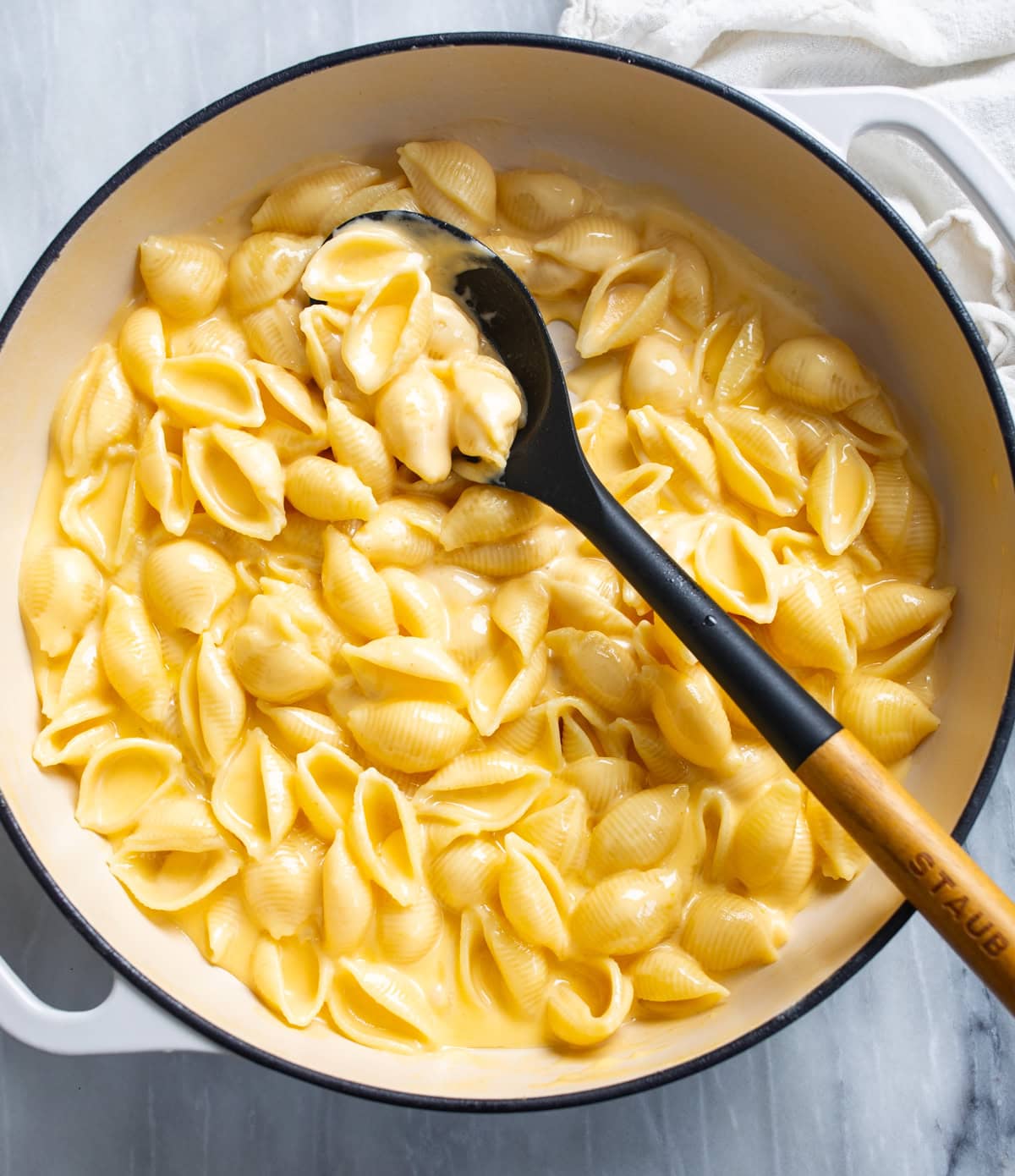 Shells and Cheese in a skillet with a a spoon scooping it up.