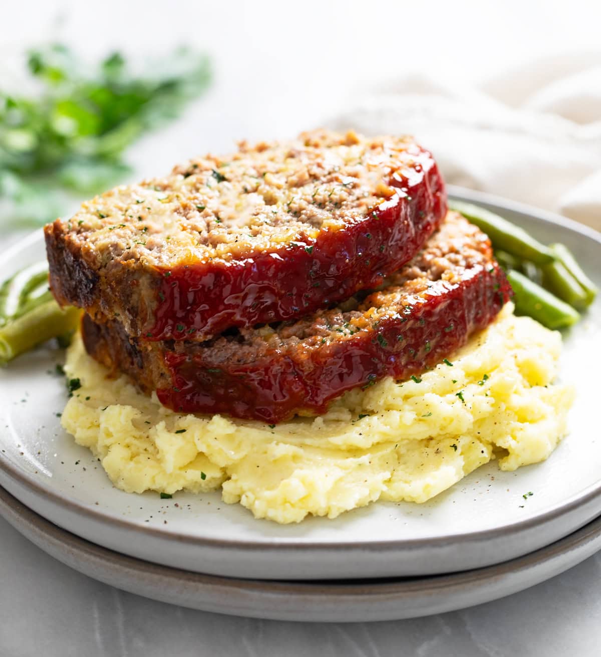 Stuffing Meatloaf on a pile of creamy mashed potatoes with green beans in the background.