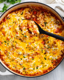 Unstuffed Peppers in a skillet with a spoon scooping it up.