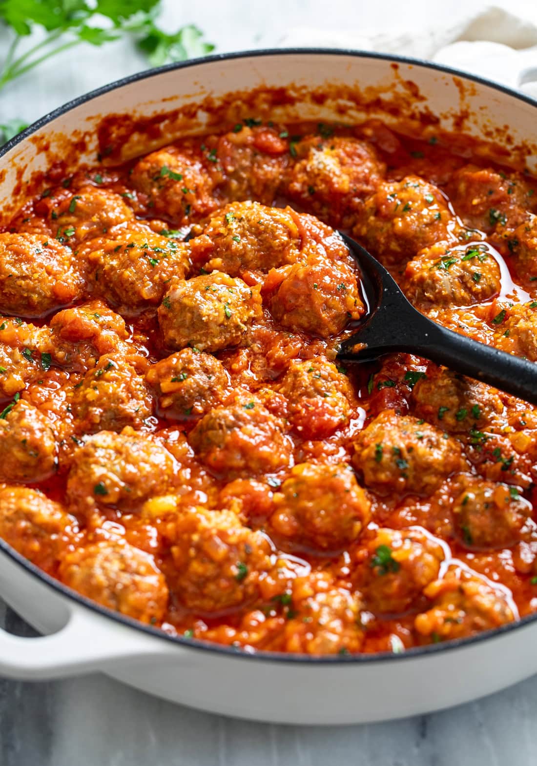 Side view of Porcupine Meatballs in a baking dish with a spoon scooping some up.