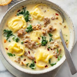 Sausage Tortellini Soup in a soup bowl with a spoon on the side.