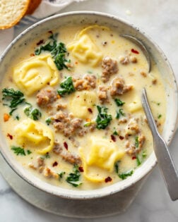 Sausage Tortellini Soup in a soup bowl with a spoon on the side.