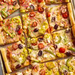 Greek Pizza with mozzarella, feta, and veggies on top.