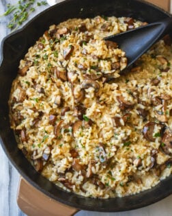 Creamy Mushroom Risotto in a skillet with fresh thyme on the side and fresh parsley on top.