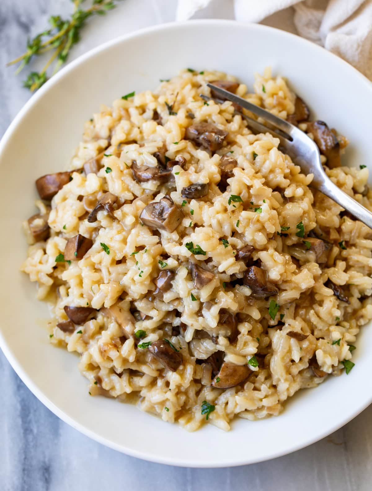 Mushroom Risotto in a white bowl with a fork on the side.