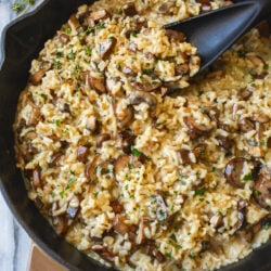 Creamy Mushroom Risotto in a skillet with fresh thyme and parsley on top.