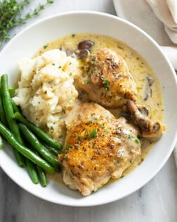 Chicken Fricassee in a white bowl with mashed potatoes and green beans.