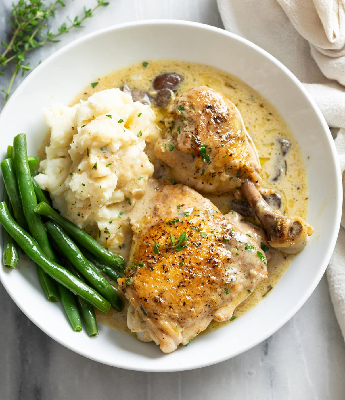 Chicken Fricassee in a white bowl with mashed potatoes and green beans.