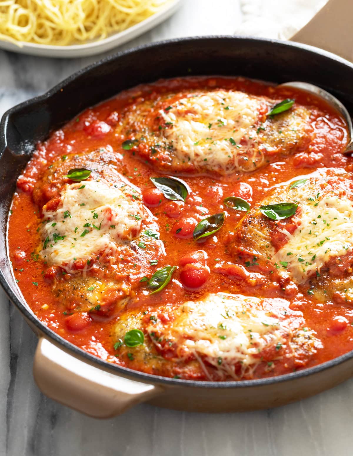 Side view of a skillet of Chicken Pomodoro with a homemade tomato sauce and chicken topped with parmesan.