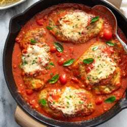 Chicken Pomodoro in a skillet with a homemade tomato sauce and fresh basil on top.