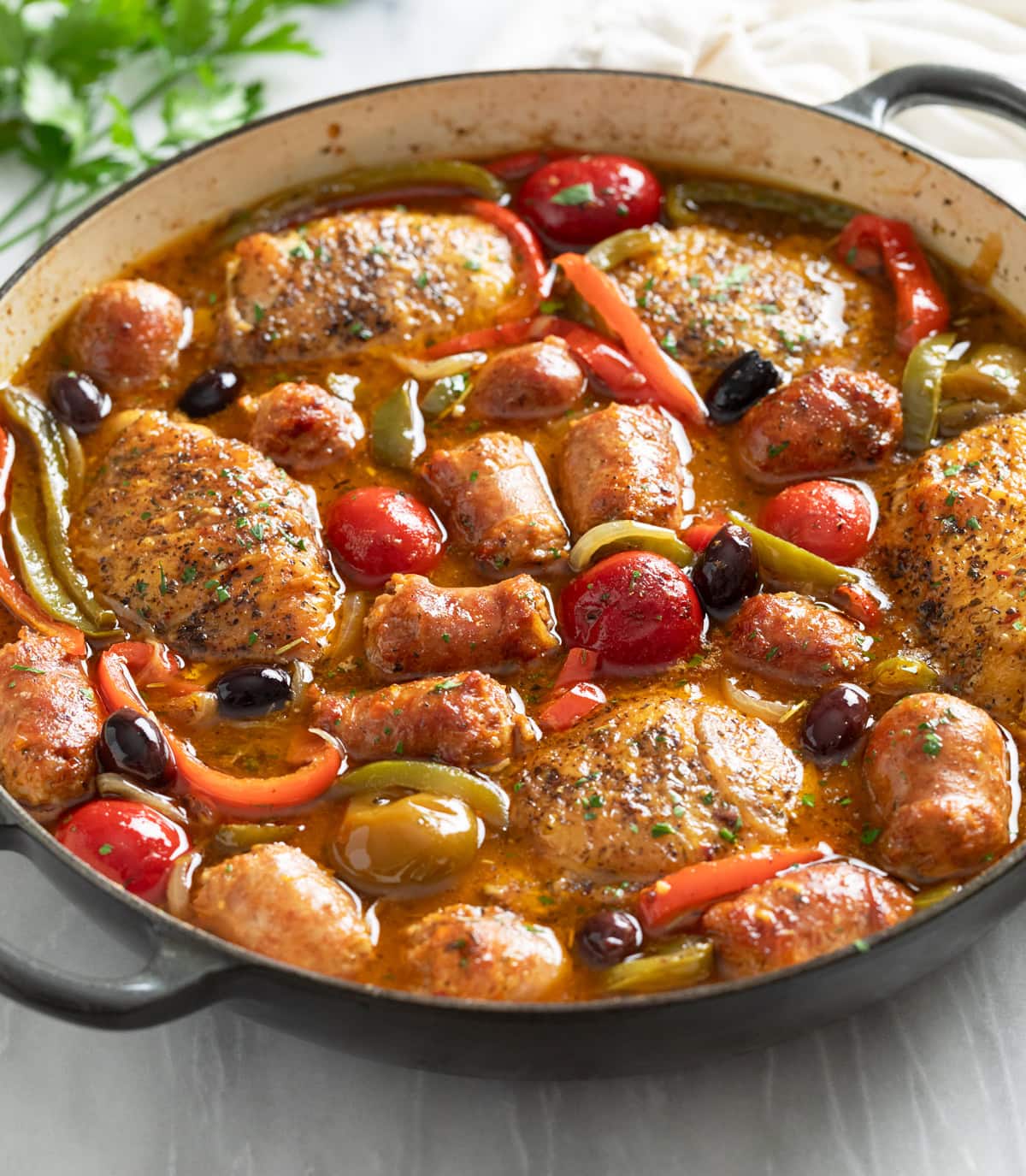 Chicken Scarpariello in a skillet with cherry peppers, bell peppers, and sauce.