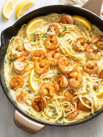 Lemon Shrimp Pasta in a skillet with lemon wedges and parsley.